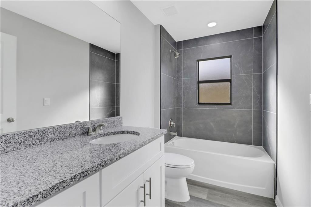 1012 Anza Avenue Lehigh Acres, FL 33971 - Photo 18 of 25 a bathroom with a granite countertop sink a toilet and bathtub