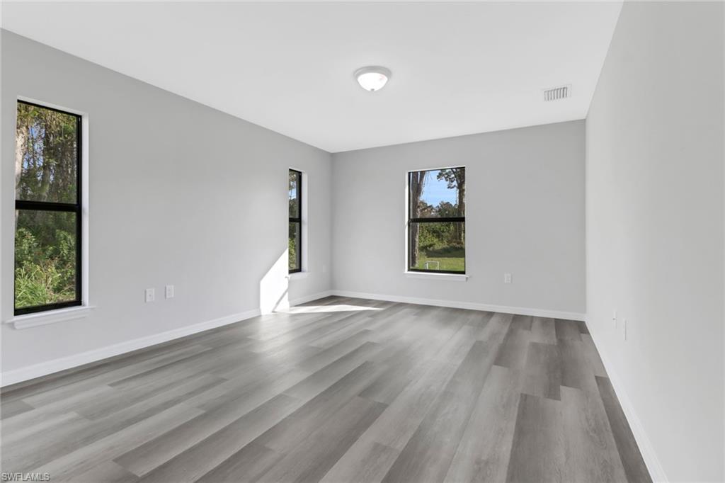 1012 Anza Avenue Lehigh Acres, FL 33971 - Photo 21 of 25 an empty room with wooden floor and windows