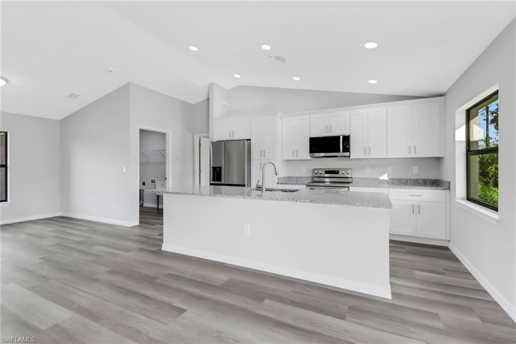 1012 Anza Avenue Lehigh Acres, FL 33971 - Photo 4 of 25 a living room with stainless steel appliances kitchen island granite countertop a stove a sink and a microwave