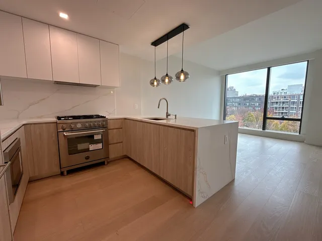 a kitchen with stainless steel appliances a sink a stove a refrigerator cabinets and a large window