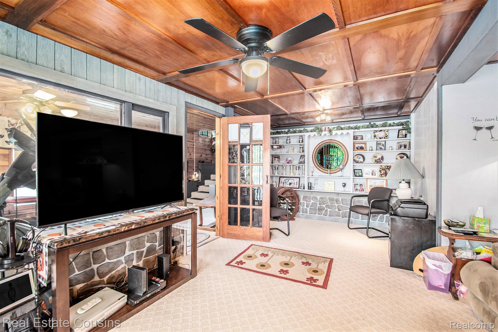 1734 Forest Road Harrison, MI 48625 - Photo 6 of 31 Carpeted office with wood walls, a wood ceiling with exposed beams, built in shelves, and ceiling fan
