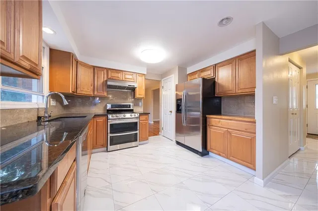 a kitchen with stainless steel appliances granite countertop a refrigerator and a stove