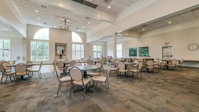 a room with lots of white furniture a window and a chandelier