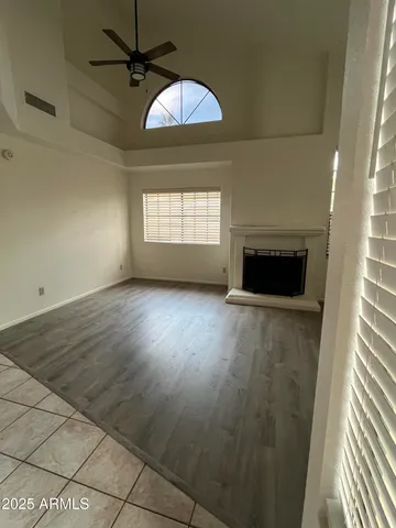 an empty room with wooden floor fireplace and windows