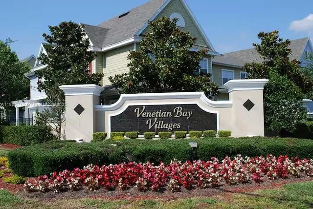 a view of a white house with a yard and flower garden