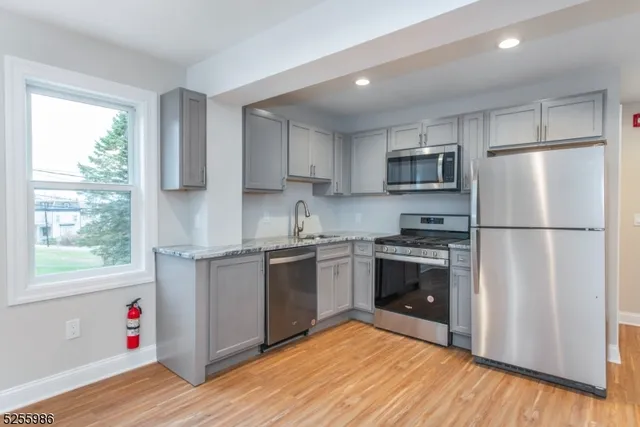 a kitchen with granite countertop a refrigerator and a stove top oven