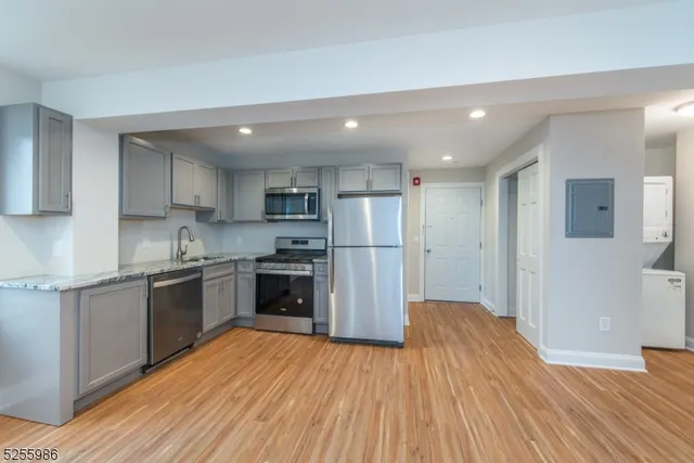 a kitchen with stainless steel appliances granite countertop a refrigerator a sink dishwasher a stove and white countertops with wooden floor