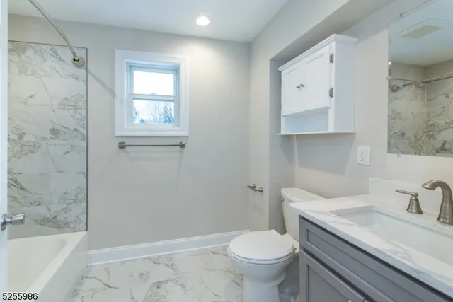 a bathroom with a granite countertop sink toilet and shower