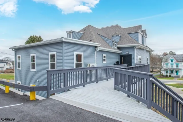a view of a house with a wooden deck and a barbeque