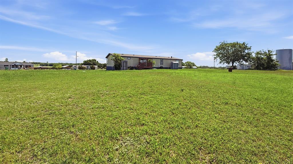 185 Private Road 4437 Rhome, TX 76078 - Photo 25 of 28 Expansive green lawn with a clear sky backdrop