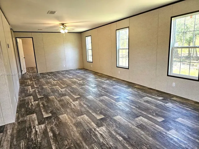 a view of an empty room with window and wooden floor