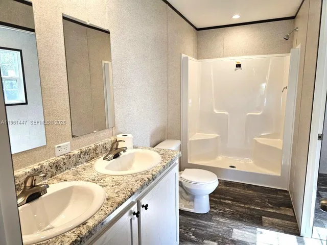 a bathroom with a granite countertop sink a toilet and shower