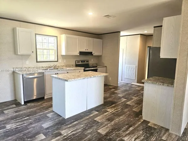 a kitchen with refrigerator a stove and white cabinets with wooden floor