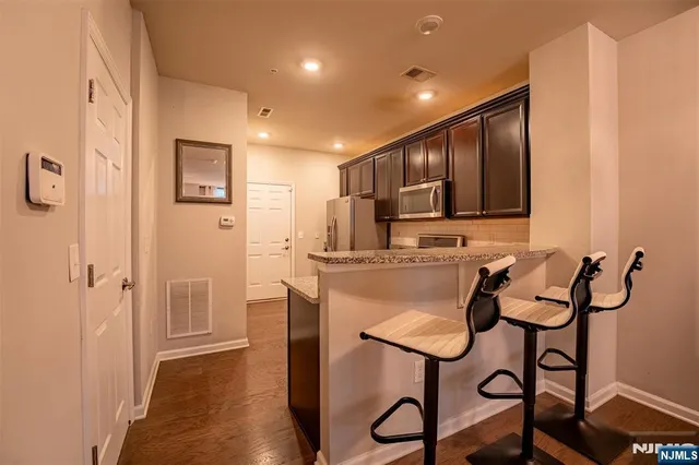 a kitchen with stainless steel appliances granite countertop a refrigerator and a stove top oven with wooden floor