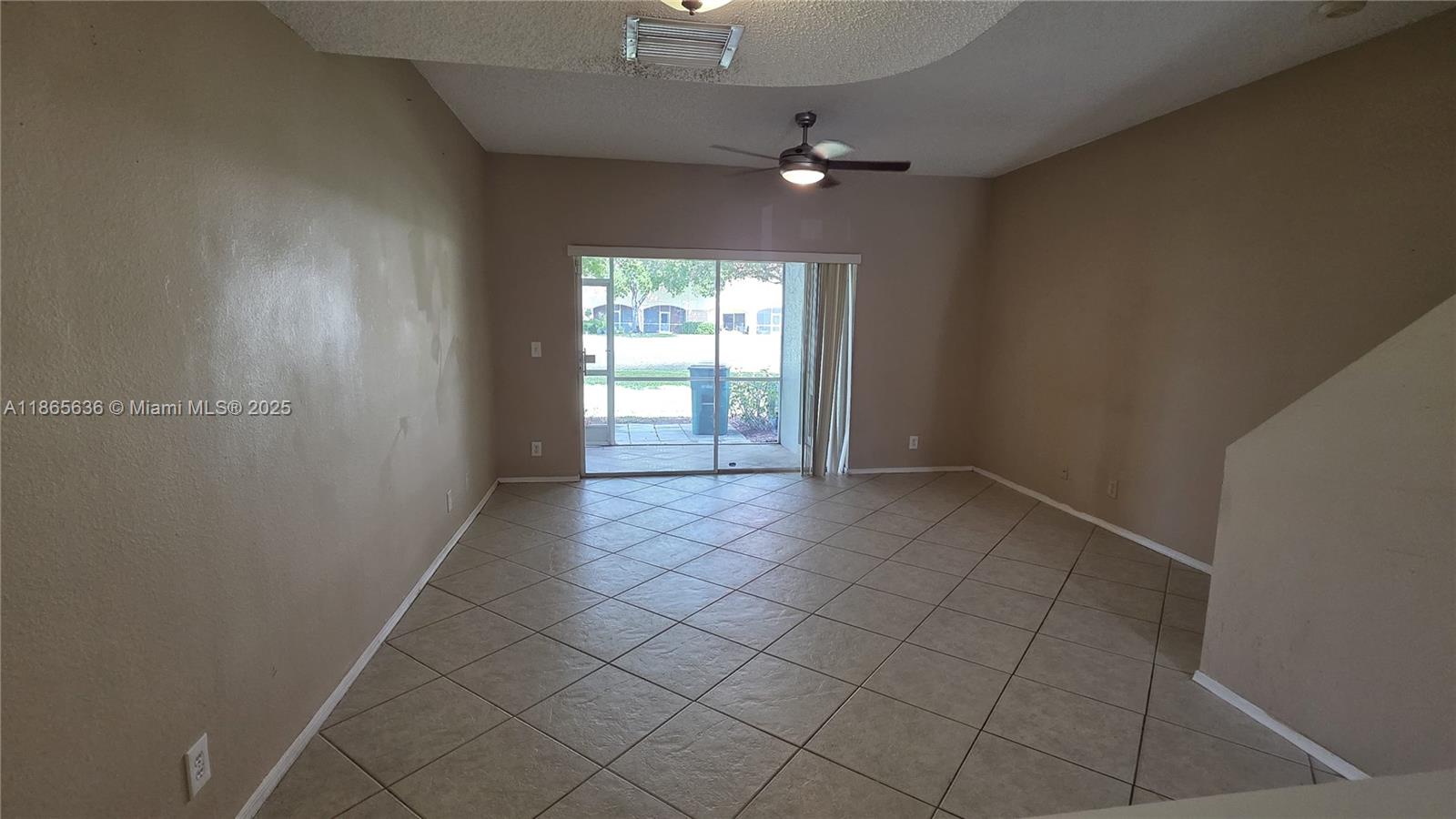 8066 Sanibel Drive, Unit 8066 Tamarac, FL 33321 - Photo 6 of 23 an empty room with chandelier fan and windows