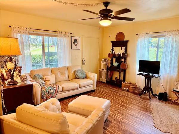 a living room with furniture a ceiling fan a flat screen tv and a window