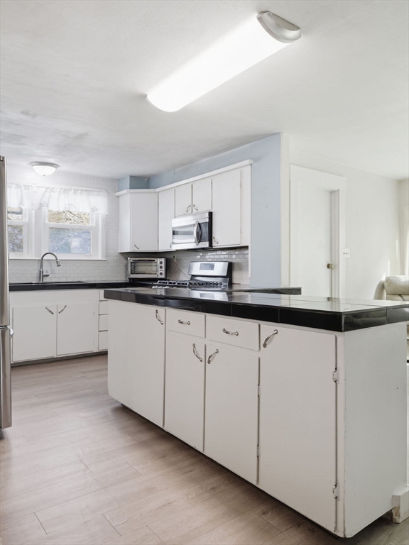 28 Court Street Lowell, MA 01852 - Photo 12 of 42 a kitchen with granite countertop white cabinets and white appliances