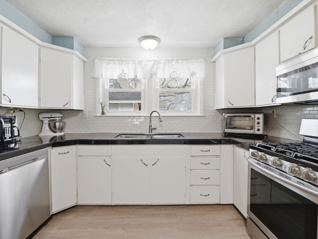 28 Court Street Lowell, MA 01852 - Photo 7 of 42 a kitchen with granite countertop white cabinets sink and stainless steel appliances