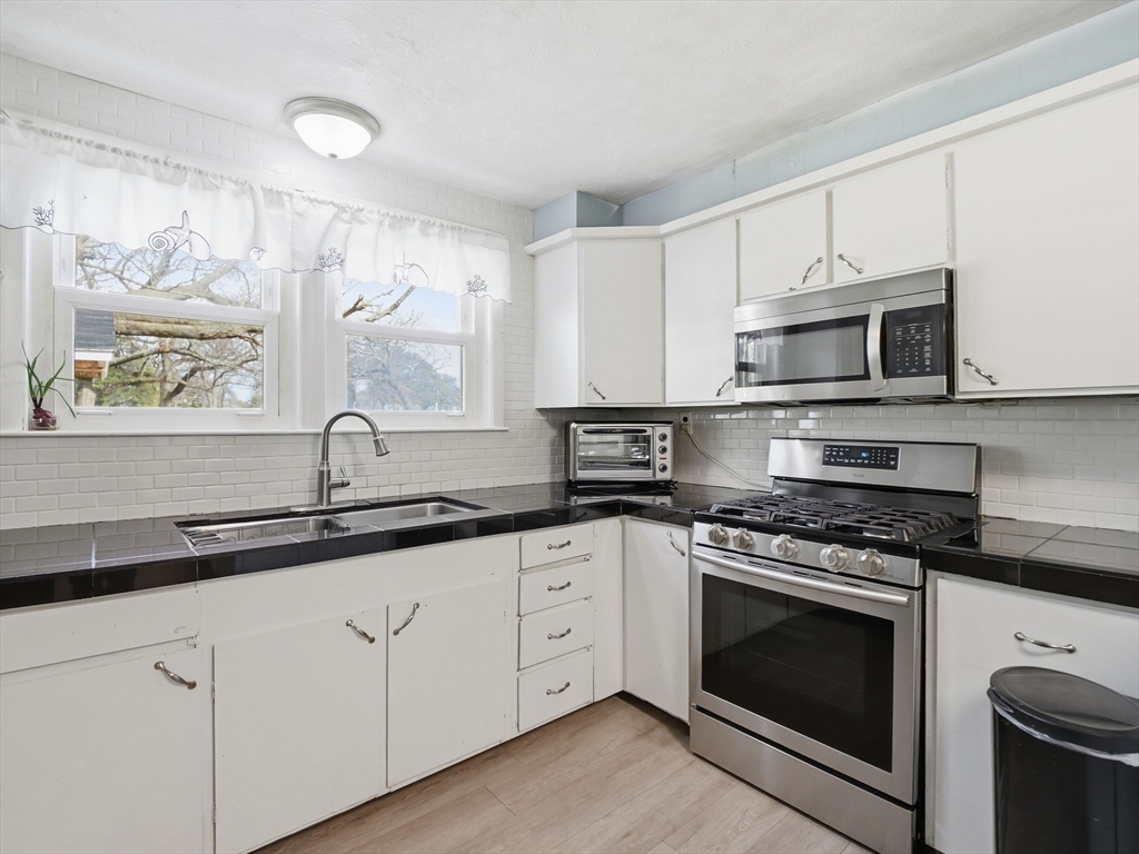 28 Court Street Lowell, MA 01852 - Photo 10 of 42 a kitchen with granite countertop white cabinets stainless steel appliances and a sink