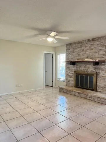 a view of empty room with kitchen and fireplace