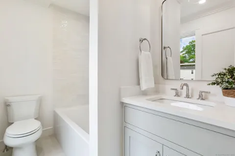a bathroom with a granite countertop sink toilet and mirror