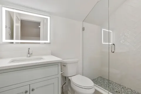 a bathroom with a sink toilet vanity and shower