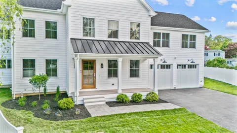 a front view of a house with a yard and potted plants