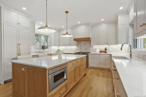 a kitchen with kitchen island granite countertop a sink a counter top space appliances and cabinets