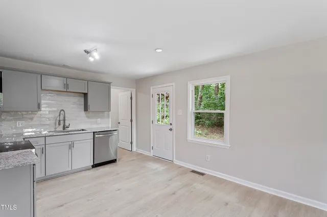 a kitchen with white cabinets appliances and window
