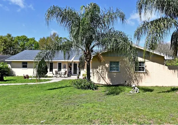 a front view of a house with a garden and trees