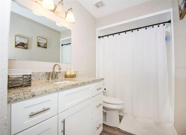 a bathroom with a granite countertop sink toilet and shower