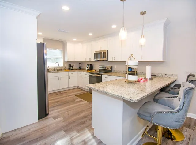 a kitchen with granite countertop kitchen island stainless steel appliances a stove a sink a refrigerator and cabinets