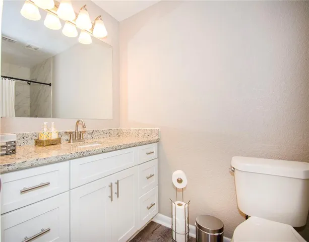 a bathroom with a granite countertop toilet sink and mirror
