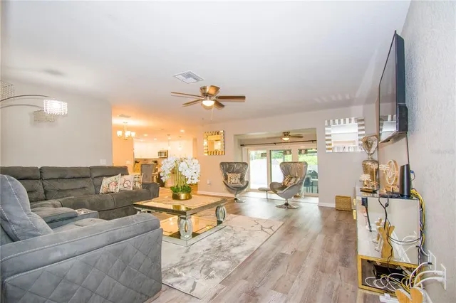 a living room with couches and kitchen view with wooden floor