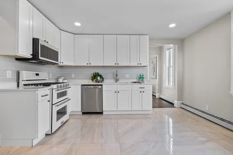 a kitchen with stainless steel appliances granite countertop a refrigerator sink and white cabinets