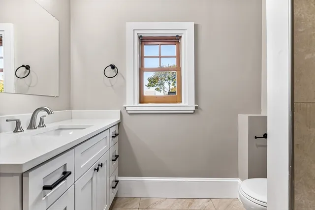 a bathroom with a granite countertop sink a toilet and shower