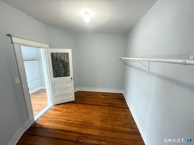 a view of empty room with wooden floor and fan
