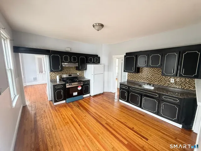 a kitchen with stainless steel appliances kitchen island granite countertop a stove a sink and a refrigerator