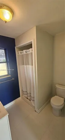 a bathroom with a toilet a sink a mirror a window and vanity