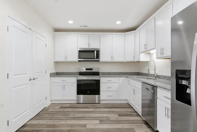 a kitchen with granite countertop white cabinets and stainless steel appliances