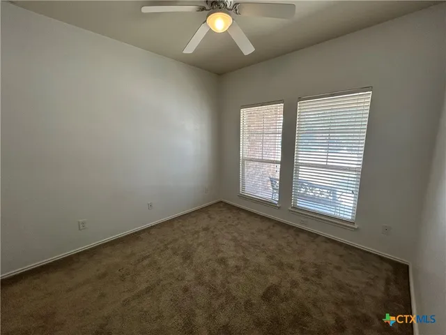 an empty room with a window and a ceiling fan