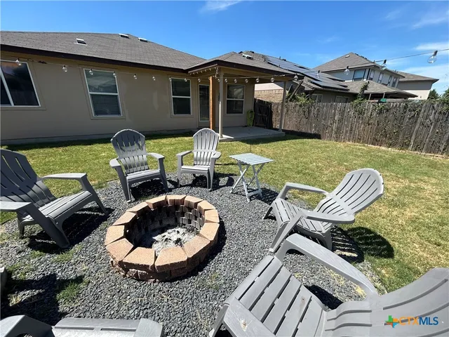 a view of a chair and tables in backyard of the house