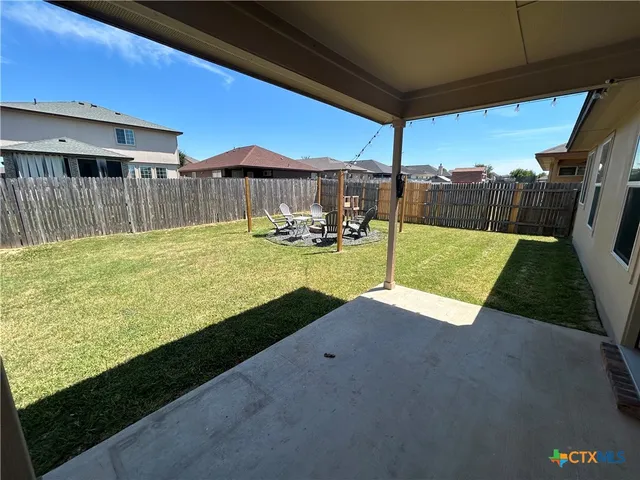 a view of a backyard with table and chairs under an umbrella