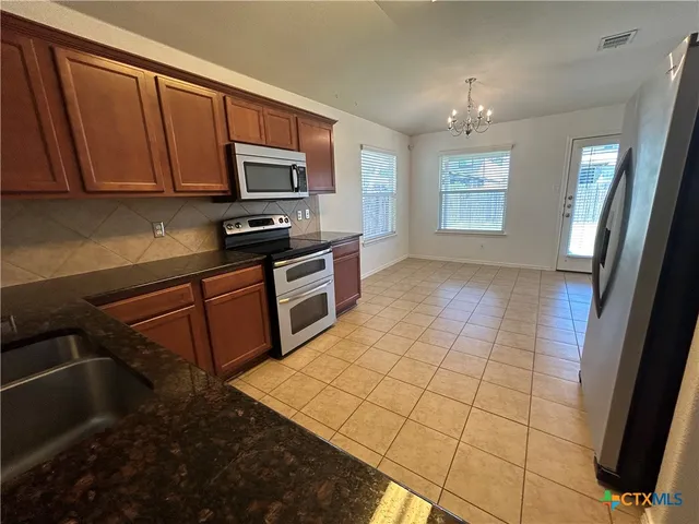 a kitchen with stainless steel appliances granite countertop a stove a sink and a microwave