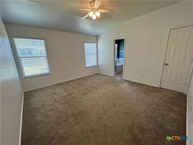 a view of an empty room with window and chandelier fan