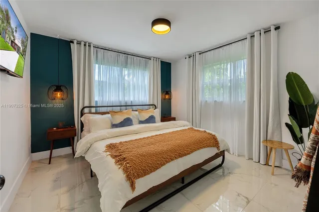 a bedroom with a bed tv and a window