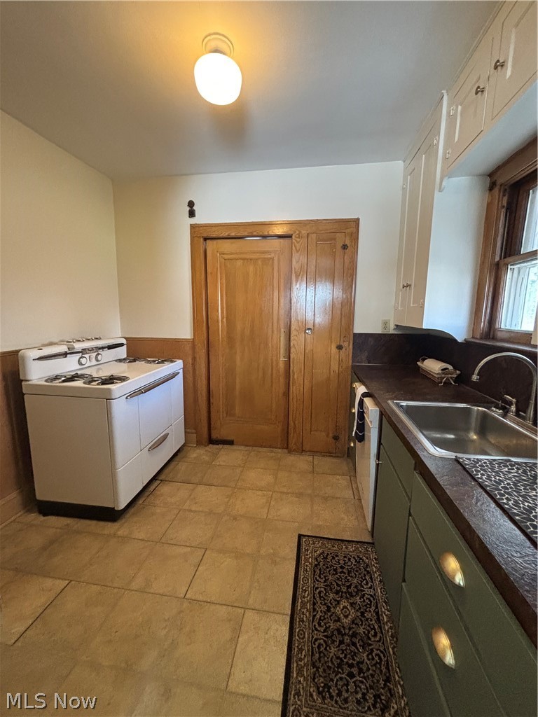 Tile flooring, built-in cabinetry, stainless steel sink, wood-finish window trim, and a white ceiling light fixture