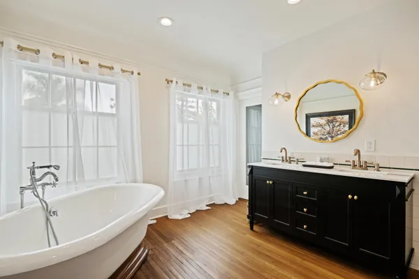a spacious bathroom with a tub sink and mirror