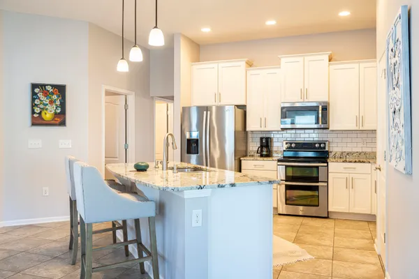 a kitchen with kitchen island granite countertop a stove a sink a dining table and chairs