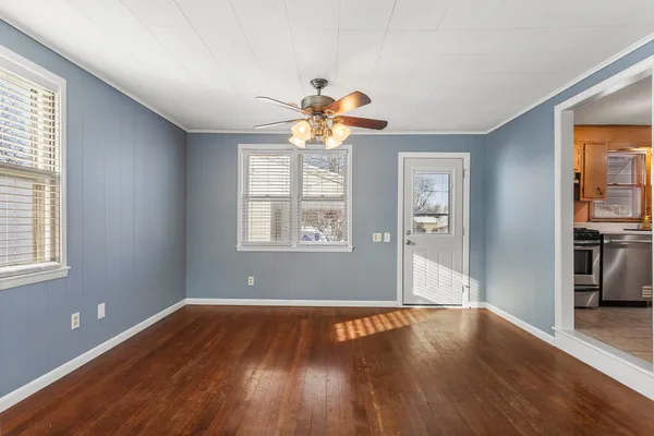 a view of an empty room with window and wooden floor